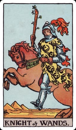 The Knight of Wands from the Rider-Waite-Smith deck: an armored knight on a rearing chestnut horse charges forward across a desert landscape, holding a budding wand aloft, his tunic and the horse's caparison patterned with salamanders, three pyramids visible in the distance.