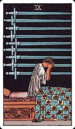 The Nine of Swords from the Rider-Waite-Smith deck: a figure sits upright in bed at night, head buried in both hands, nine swords mounted horizontally on the dark wall behind them, the quilt below decorated with roses and astrological symbols, a carved panel on the bed showing one figure attacking another.