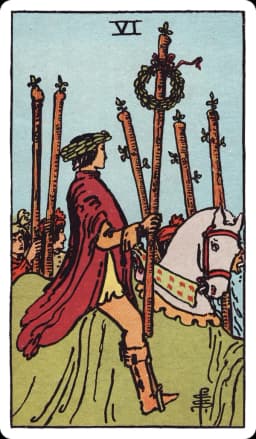 The Six of Wands from the Rider-Waite-Smith deck: a rider on a white horse wears a laurel wreath and carries a wand topped with another laurel wreath, moving through a crowd of people on foot who raise their own wands as he passes.