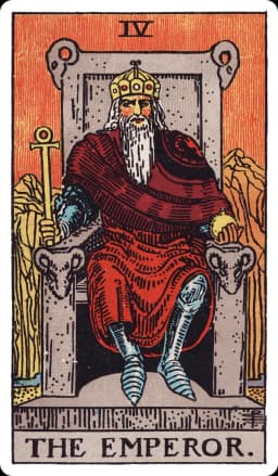 The Emperor from the Rider-Waite-Smith deck: a bearded older man in red robes and armor sits on a stone throne carved with four ram's heads, holding an ankh-topped scepter in one hand and a golden orb in the other, with barren, rocky red mountains rising behind him.