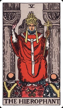 The Hierophant from the Rider-Waite-Smith deck: a robed figure wearing a triple-tiered papal crown sits enthroned between two grey pillars, right hand raised in a two-fingered gesture of benediction, a triple-barred cross staff in his left hand, two crossed keys resting at the base of his throne, and two tonsured acolytes kneeling before him, their robes patterned with lilies and roses.