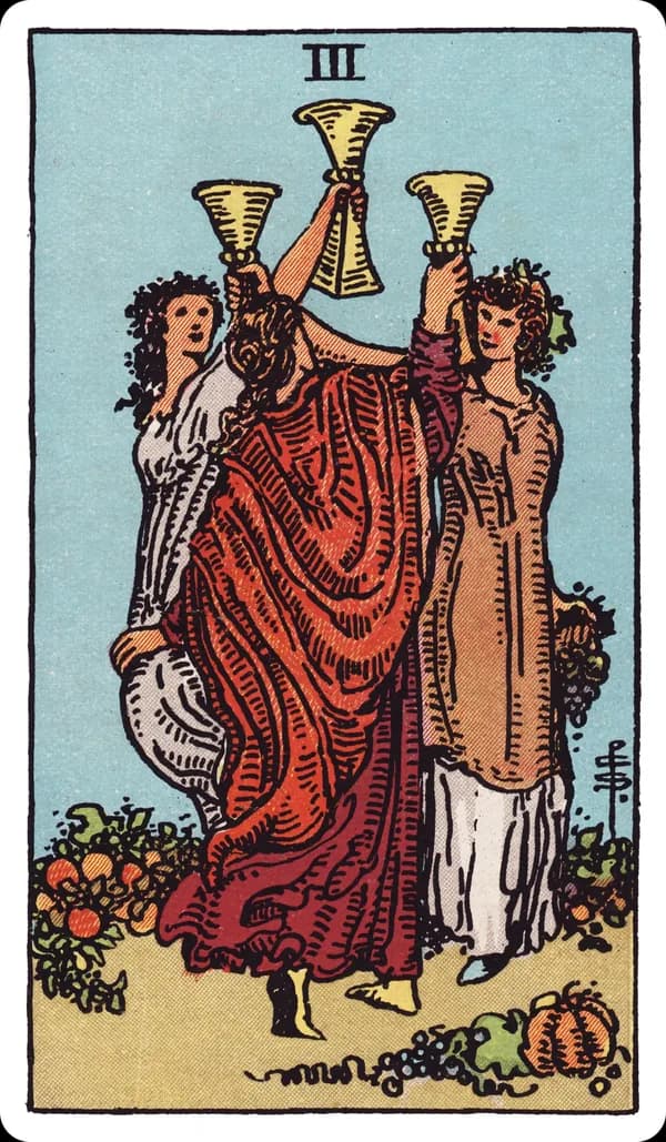 The Three of Cups from the Rider-Waite-Smith deck: three women dance in a circle in a garden, each raising a cup high in a toast, wearing crowns of flowers and fruit; gourds, grapes, and pumpkins lie scattered at their feet.